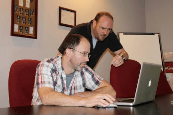 Ben Abray (President of Autumn Graphics) and Ian Dobie (Customer Service Manager) at desk, looking at laptop