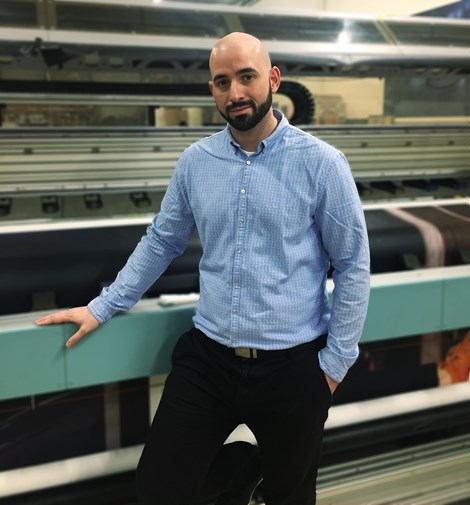 Ateliers Cassandre employee standing by prepress machines