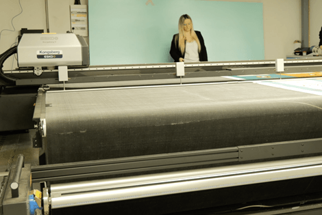 Ateliers Cassandre employee operating a Kongsberg cutting table machine