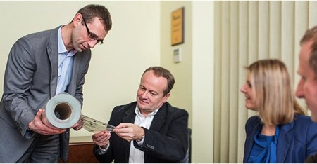 Photo of Skanem employees viewing sheet of labels