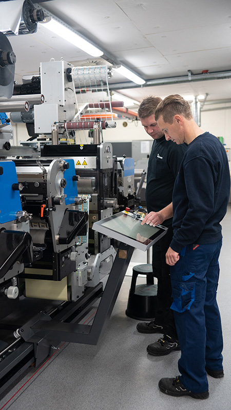Photo of Skanem employees operating a prepress machine